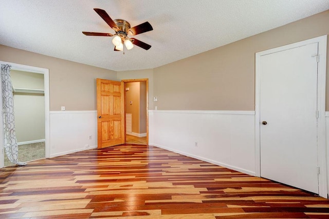 2049 Saunders Rd, Ringgold, GA 30736 - unfurnished bedroom with wood finished floors, a wainscoted wall, a textured ceiling, a closet, and ceiling fan