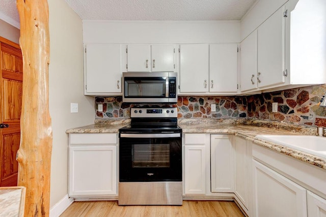2049 Saunders Rd, Ringgold, GA 30736 - kitchen with stainless steel microwave, range with electric cooktop, light wood finished floors, tasteful backsplash, and a textured ceiling