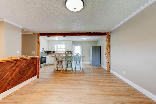 2049 Saunders Rd, Ringgold, GA 30736 - kitchen with stainless steel appliances, white cabinetry, a textured ceiling, light wood-style flooring, and a breakfast bar