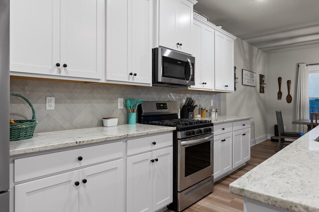 7559 Snow Cone Way, Ooltewah, TN 37363 - kitchen featuring appliances with stainless steel finishes, light wood-type flooring, white cabinets, and decorative backsplash