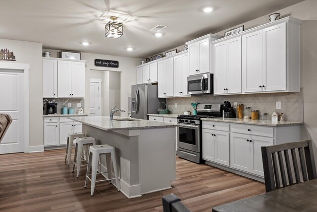 7559 Snow Cone Way, Ooltewah, TN 37363 - kitchen with stainless steel appliances, a sink, wood finished floors, a breakfast bar area, and tasteful backsplash