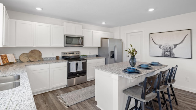 314 Draft St, Rossville, GA 30741 - kitchen with appliances with stainless steel finishes, white cabinetry, a breakfast bar, dark wood-style flooring, and a kitchen island