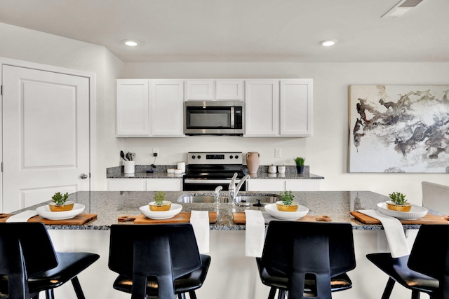 300 Draft St, Rossville, GA 30741 - kitchen with appliances with stainless steel finishes, dark stone countertops, a breakfast bar, recessed lighting, and white cabinets