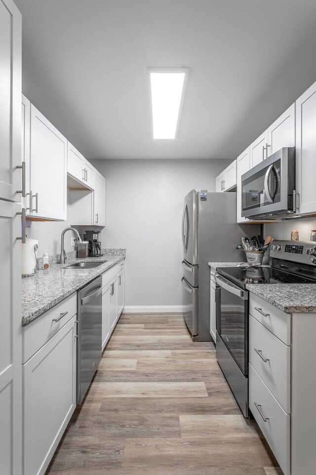 900 Mountain Creek Rd Unit 300, Chattanooga, TN 37405 - kitchen featuring stainless steel appliances, a sink, baseboards, white cabinets, and light wood-style flooring