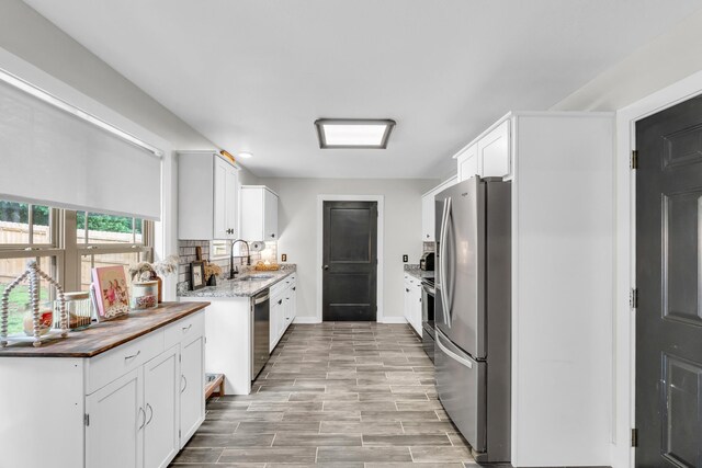 329 Windsong Dr, Lafayette, GA 30728 - kitchen with appliances with stainless steel finishes, a sink, white cabinetry, backsplash, and baseboards