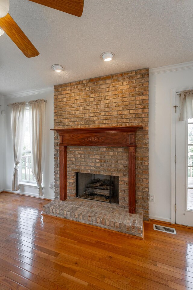 8275 Stillwater Cir, Ooltewah, TN 37363 - detailed view of a brick fireplace, a textured ceiling, wood finished floors, ornamental molding, and ceiling fan