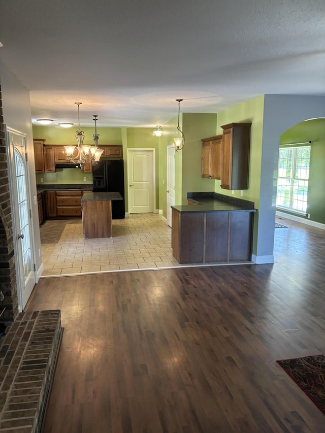 12466 Alabama Hwy, Ringgold, GA 30736 - kitchen featuring black refrigerator with ice dispenser, dark countertops, wood finished floors, a kitchen island, and arched walkways