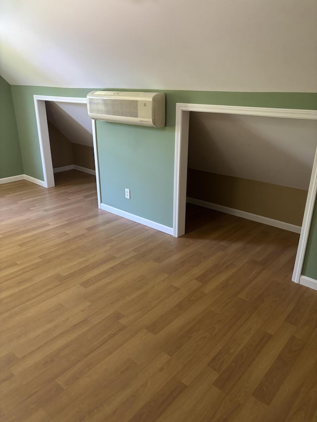 12466 Alabama Hwy, Ringgold, GA 30736 - unfurnished bedroom featuring light wood-type flooring, vaulted ceiling, a wall unit AC, and baseboards