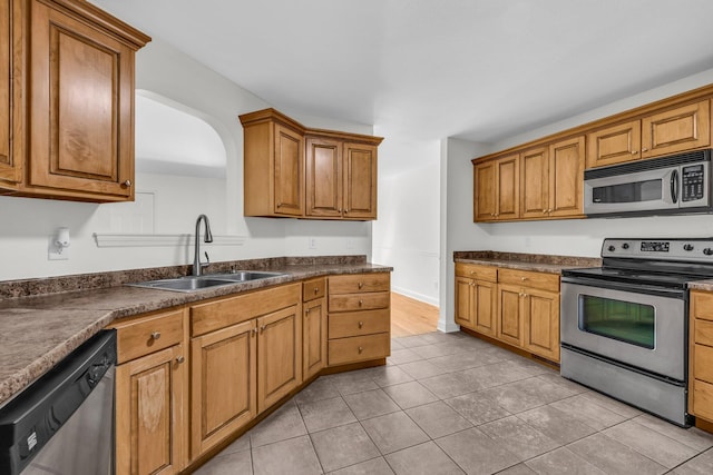 1770 Thrasher Pike, Hixson, TN 37343 - kitchen with stainless steel appliances, a sink, dark countertops, brown cabinets, and light tile patterned floors