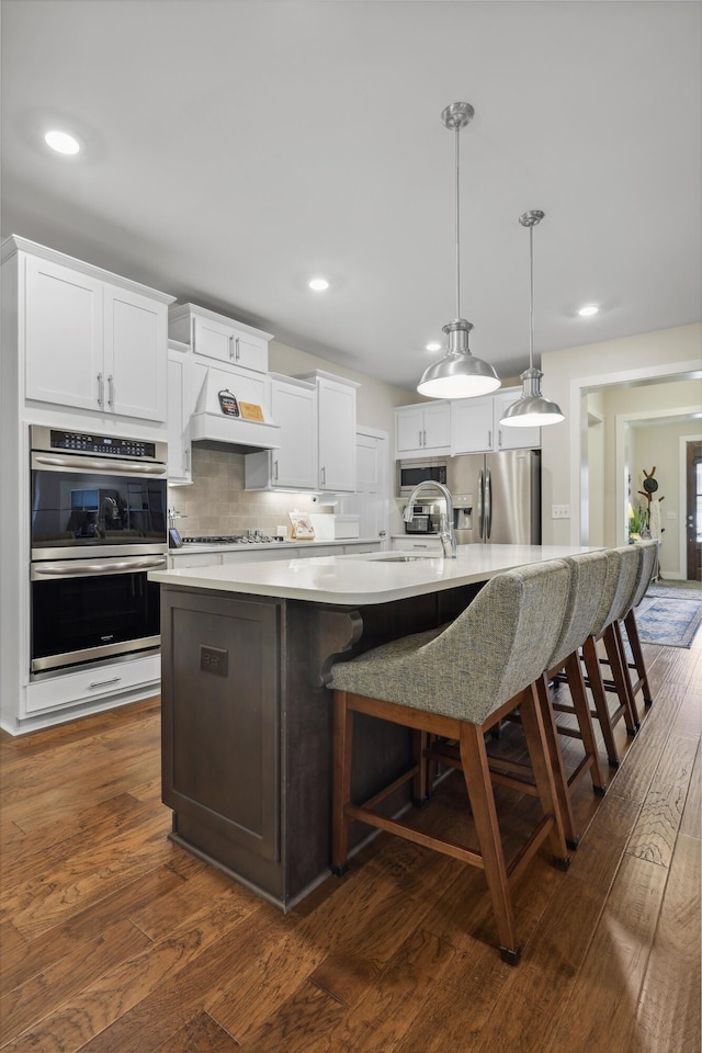 1590 Buttonwood Unit 20, Chattanooga, TN 37421 - kitchen featuring appliances with stainless steel finishes, a large island with sink, decorative backsplash, a sink, and dark wood finished floors
