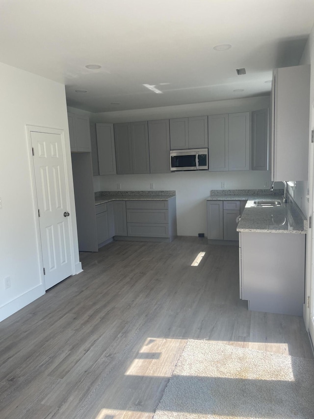 2105 Wisdom St, Chattanooga, TN 37406 - kitchen with stainless steel microwave, gray cabinets, wood finished floors, and light stone counters