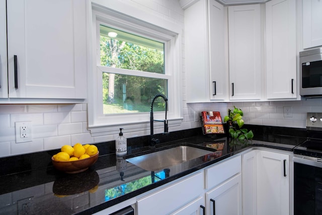 1306 Phyllis Ln, Chattanooga, TN 37421 - kitchen with appliances with stainless steel finishes, a sink, white cabinetry, dark stone countertops, and tasteful backsplash
