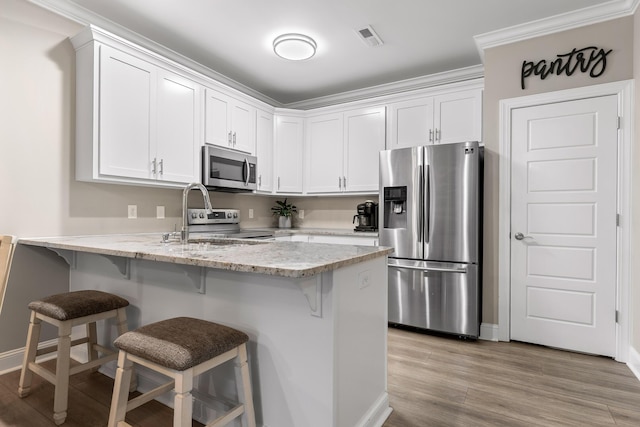 214 Camden Way Unit 38, Dalton, GA 30721 - kitchen with stainless steel appliances, a peninsula, white cabinetry, a kitchen bar, and ornamental molding