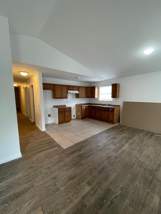 2107 Stuart St, Chattanooga, TN 37406 - kitchen featuring wood finished floors, vaulted ceiling, under cabinet range hood, a sink, and brown cabinets