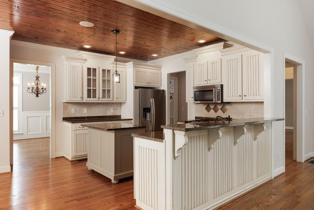 8650 Homecoming Dr, Chattanooga, TN 37421 - kitchen featuring stainless steel appliances, a peninsula, glass insert cabinets, decorative backsplash, and a kitchen breakfast bar