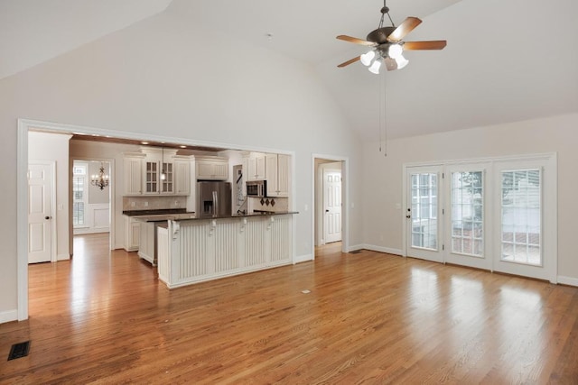 8650 Homecoming Dr, Chattanooga, TN 37421 - unfurnished living room with high vaulted ceiling, a ceiling fan, a chandelier, light wood-style flooring, and baseboards