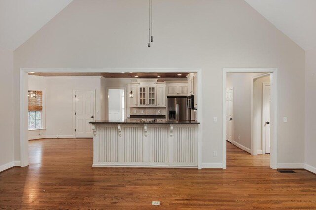 8650 Homecoming Dr, Chattanooga, TN 37421 - kitchen with stainless steel fridge with ice dispenser, high vaulted ceiling, dark countertops, a breakfast bar area, and glass insert cabinets
