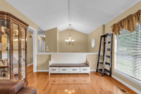 270 Rolling Meadows Dr, Ringgold, GA 30736 - living area featuring a chandelier, light wood finished floors, vaulted ceiling, baseboards, and healthy amount of natural light