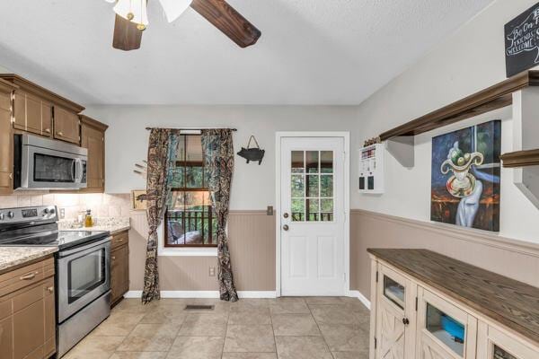 270 Rolling Meadows Dr, Ringgold, GA 30736 - kitchen featuring appliances with stainless steel finishes, a wainscoted wall, a ceiling fan, light tile patterned floors, and baseboards