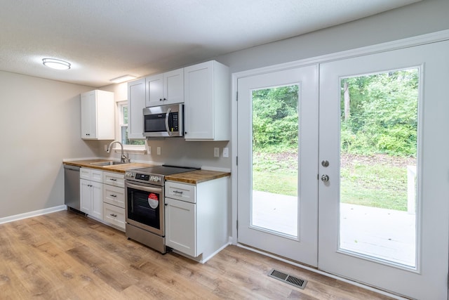 8539 Ricardo Ln, Hixson, TN 37343 - kitchen featuring stainless steel appliances, a sink, wood counters, light wood-style floors, and white cabinets