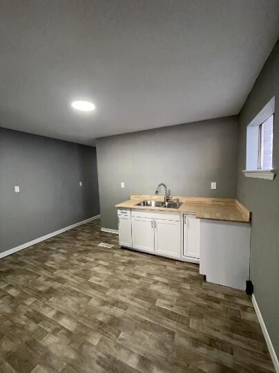 kitchen featuring butcher block counters, white cabinetry, and dark flooring