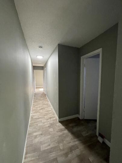 hallway with wood finished floors and baseboards