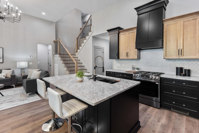 300 Dogwood Ln, Fort Oglethorpe, GA 30742 - kitchen with stainless steel range with gas stovetop, range hood, an island with sink, decorative backsplash, and light stone countertops