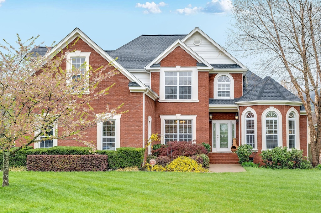 7532 Tranquility Dr, Ooltewah, TN 37363 - traditional-style home with a front yard, brick siding, and a shingled roof