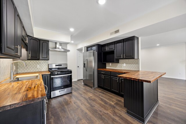2138 Vaden Village Dr, Chattanooga, TN 37421 - kitchen featuring appliances with stainless steel finishes, wooden counters, wall chimney range hood, tasteful backsplash, and dark wood-style floors