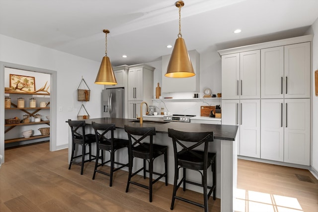 6430 Dharma Loop, Chattanooga, TN 37412 - kitchen featuring stainless steel appliances, a kitchen island with sink, open shelves, a breakfast bar area, and light wood finished floors