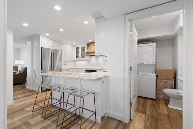 1131 Stringers Ridge Rd Unit 12E, Chattanooga, TN 37405 - kitchen with stacked washer / drying machine, a peninsula, white cabinetry, light countertops, and light wood-style flooring