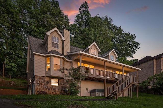 1714 S Crest Manor Ln, Chattanooga, TN 37404 - back of house at dusk with stone siding, stairway, a chimney, and a lawn