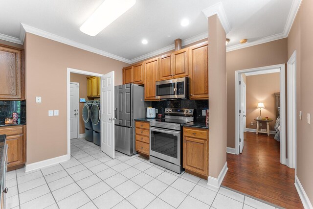 4322 Wellesley Dr, Ooltewah, TN 37363 - kitchen with stainless steel appliances, separate washer and dryer, dark countertops, decorative backsplash, and ornamental molding