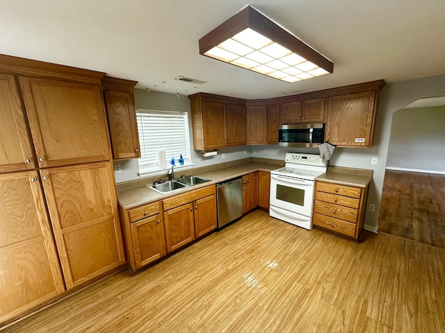 219 Igou Ferry Rd, Soddy Daisy, TN 37379 - kitchen featuring stainless steel appliances, a sink, light wood-type flooring, brown cabinetry, and light countertops