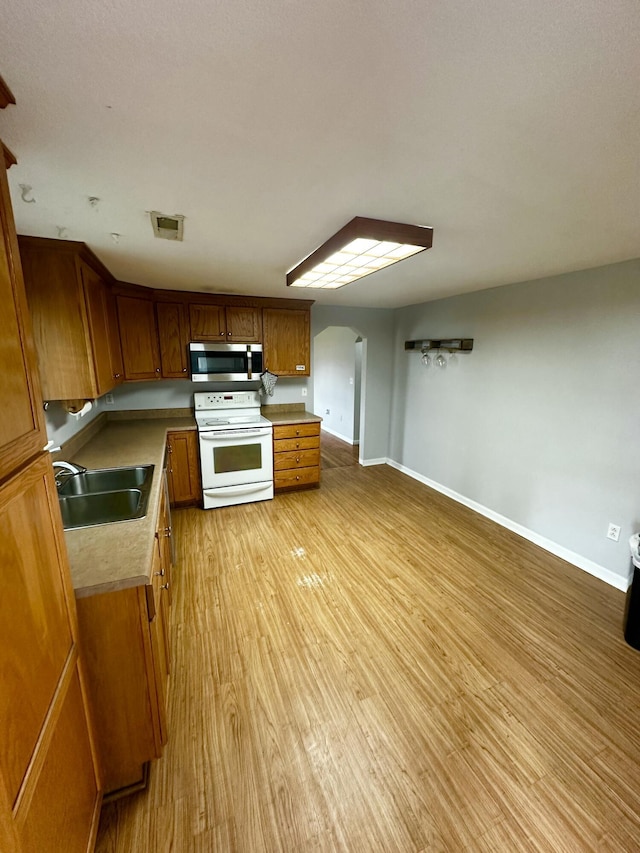 219 Igou Ferry Rd, Soddy Daisy, TN 37379 - kitchen with white electric stove, stainless steel microwave, a sink, light wood-type flooring, and arched walkways