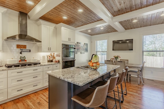 8870 Silver Maple Dr, Ooltewah, TN 37363 - kitchen featuring wall chimney exhaust hood, stainless steel gas cooktop, light wood-type flooring, wood ceiling with exposed beams, and plenty of natural light
