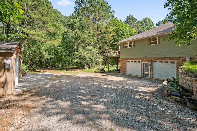 204 Chapman Ct, Lafayette, GA 30728 - view of side of home featuring gravel driveway, an attached garage, a forest view, and brick siding