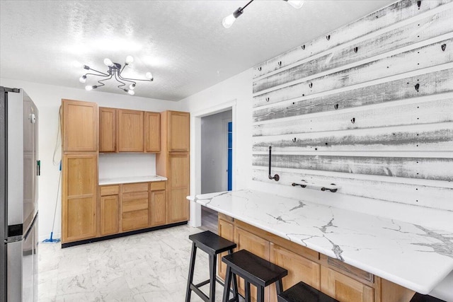 536 Sequatchie Ln, Sequatchie, TN 37374 - kitchen featuring stainless steel refrigerator, light marble finish flooring, a kitchen breakfast bar, and a textured ceiling
