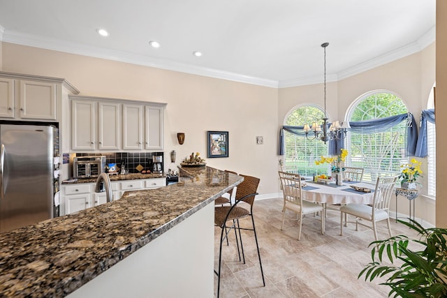 902 Cattails Dr, Ooltewah, TN 37363 - kitchen featuring freestanding refrigerator, baseboards, backsplash, ornamental molding, and dark stone counters