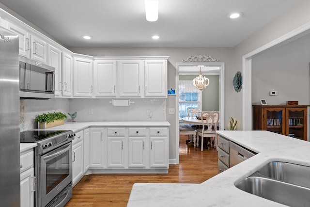 102 Water Mill Trce, Ringgold, GA 30736 - kitchen with appliances with stainless steel finishes, light countertops, a chandelier, light wood finished floors, and white cabinetry