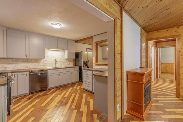 252 Valley View Dr, Dunlap, TN 37327 - kitchen featuring appliances with stainless steel finishes, a sink, wooden walls, light wood-type flooring, and decorative backsplash