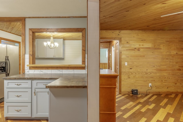 252 Valley View Dr, Dunlap, TN 37327 - kitchen with stainless steel fridge, wooden walls, light wood-style flooring, white cabinets, and a chandelier