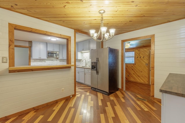 252 Valley View Dr, Dunlap, TN 37327 - kitchen with stainless steel appliances, light wood-type flooring, a chandelier, decorative backsplash, and wood walls
