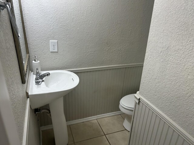 3955 Teakwood Dr, Chattanooga, TN 37416 - bathroom featuring a textured wall, toilet, tile patterned flooring, baseboards, and a wainscoted wall