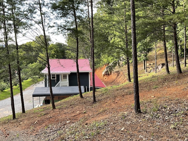690 Ditch Gap Rd, Whitwell, TN 37397 - view of front facade with metal roof, covered porch, a wooded view, and dirt driveway