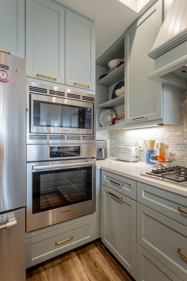 200 Manufacturers Rd Apt 507, Chattanooga, TN 37405 - kitchen with stainless steel appliances, premium range hood, wood finished floors, and backsplash