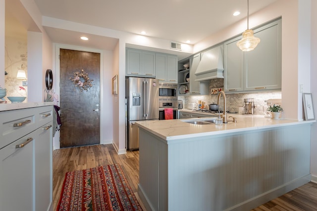 200 Manufacturers Rd Apt 507, Chattanooga, TN 37405 - kitchen featuring appliances with stainless steel finishes, a peninsula, light wood-style flooring, tasteful backsplash, and custom range hood