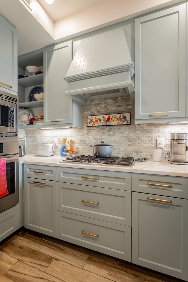 200 Manufacturers Rd Apt 507, Chattanooga, TN 37405 - kitchen featuring light countertops, stainless steel appliances, backsplash, open shelves, and wood finished floors