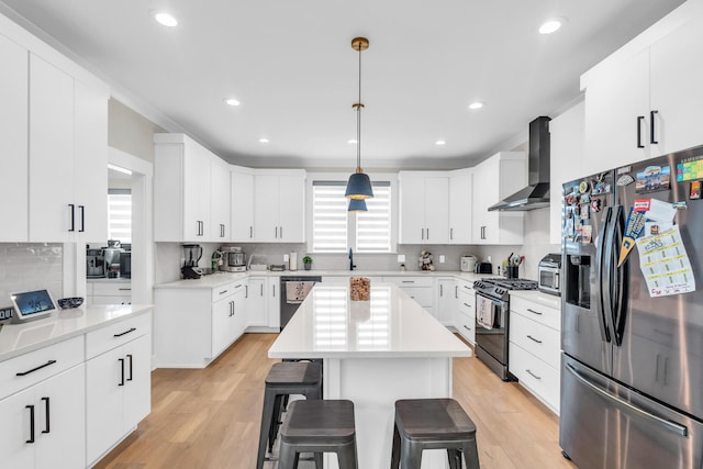 9257 Skyfall Dr, Ooltewah, TN 37363 - kitchen featuring stainless steel appliances, wall chimney exhaust hood, a kitchen bar, tasteful backsplash, and light wood-style flooring