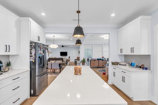 9257 Skyfall Dr, Ooltewah, TN 37363 - kitchen with stainless steel fridge, open floor plan, a ceiling fan, a center island, and white cabinetry
